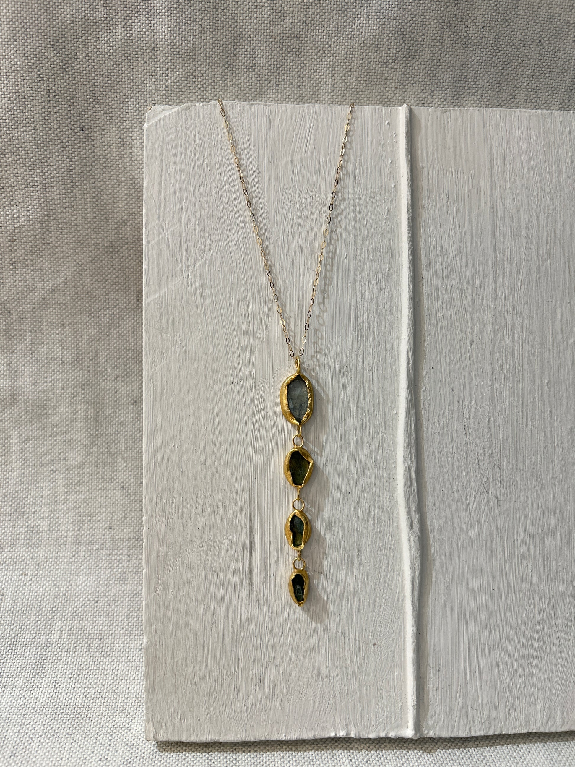 Necklace with gold pendant on a textured white surface