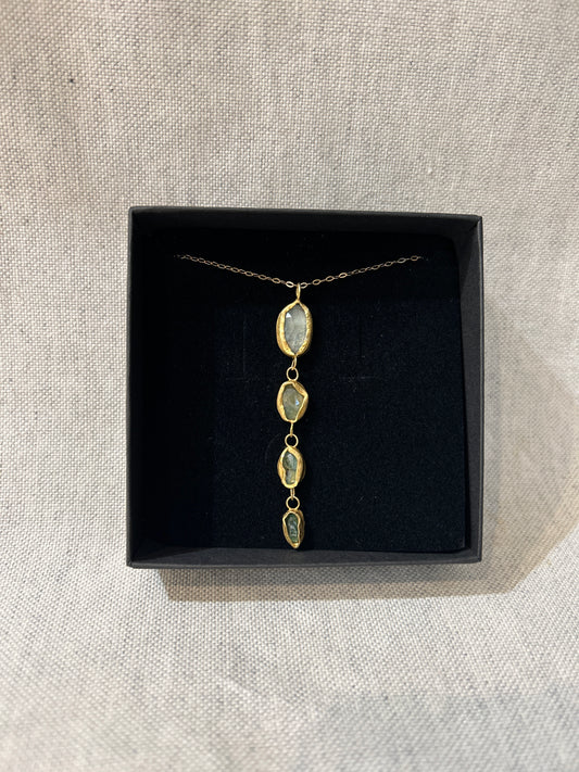 Gold necklace with a pendant in a black box on a beige fabric background