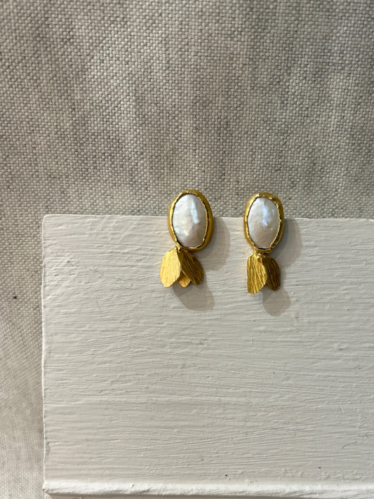 Pair of gold earrings with a pearl on a textured surface
