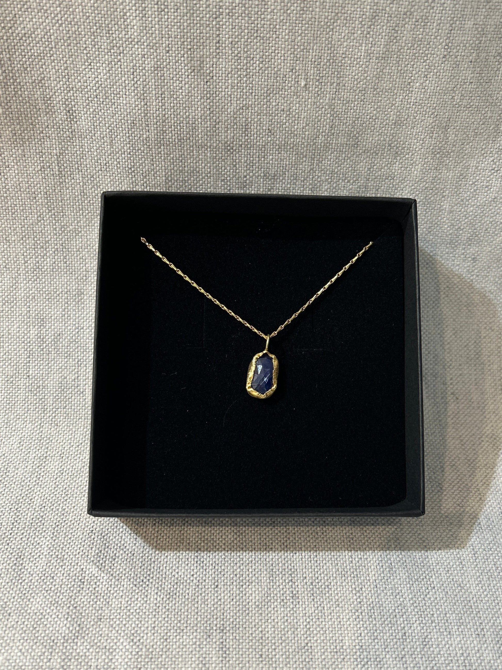 Necklace with a pendant in a black box on a textured gray surface