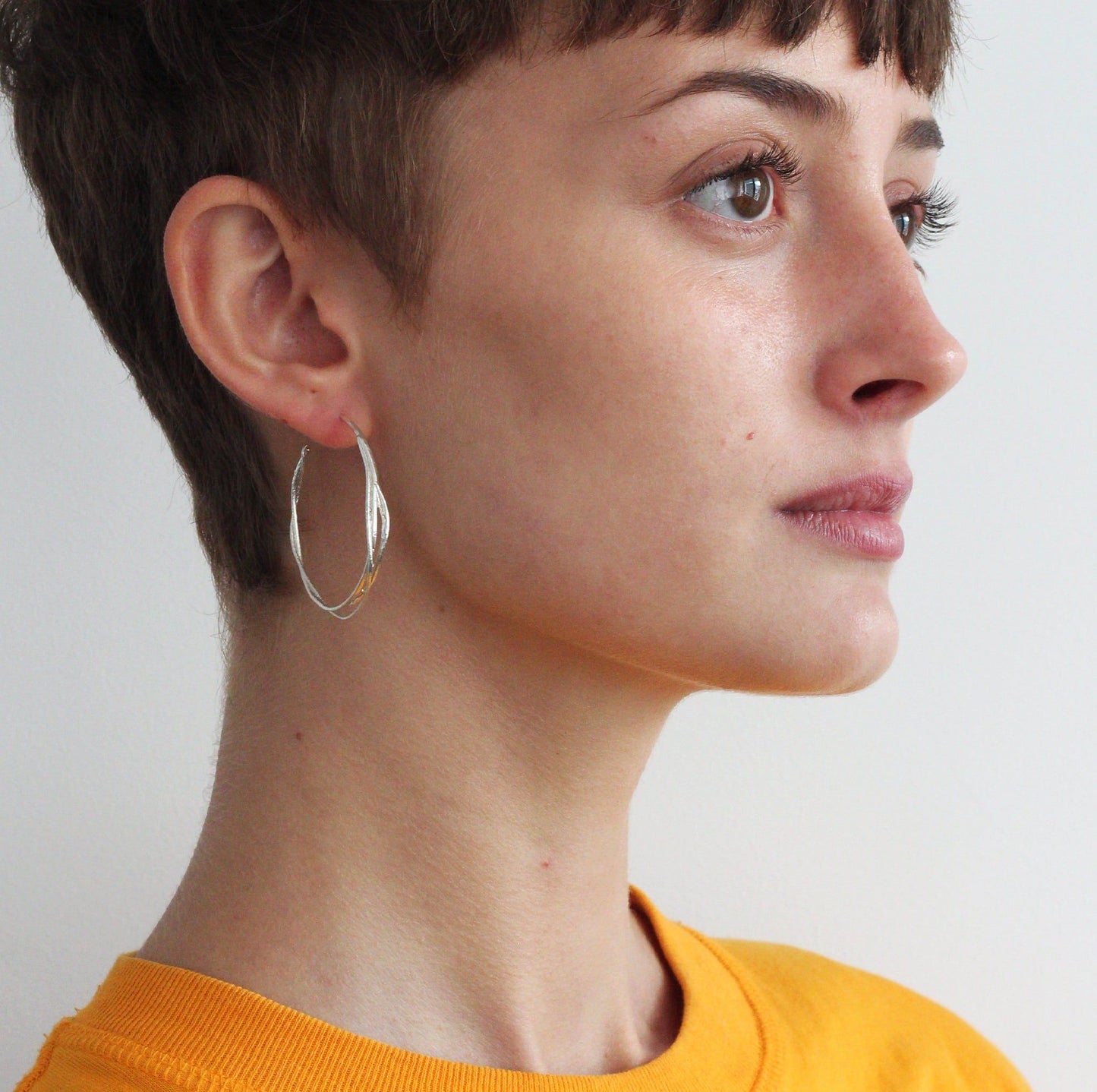 model wearing silver twist hoops