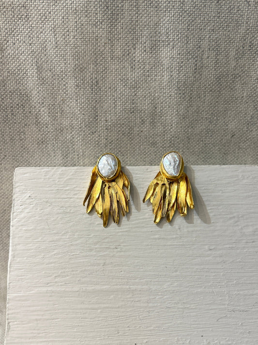 Gold leaf-shaped earrings with a central pearl on a light gray background